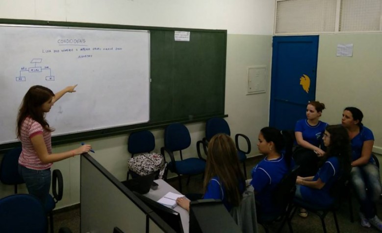 Meninas são orientadas em exercicío sobre linguagem de programação